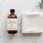 Fresh facial cleanser and white washcloth on a marble counter.